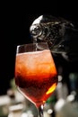 The barman making Aperol Spritz cocktail pours water into the glass with ice