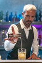 Barman making cocktail in night club adding ingredients and creating expert drinks on bar counter. Royalty Free Stock Photo