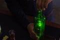 A barman is opening a green liquor bottle