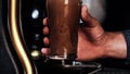 Barman in plaid shirt pouring a pint of cold dark beer into a clear glass Royalty Free Stock Photo