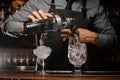 Barman pouring alcoholic drink into a glass using a jigger to prepare a cocktail Royalty Free Stock Photo