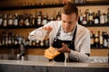 Barman pouring alcoholic drink mixed with ice into a glass