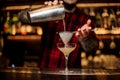 Barman pouring juicy alcoholic cocktail from shaker into cocktail glass using strainer Royalty Free Stock Photo