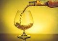 Barman pouring snifter of brandy in elegant typical cognac glass on table