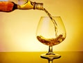 Barman pouring snifter of brandy in elegant typical cognac glass on table