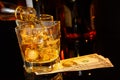 Barman pouring whiskey in front of whisky glass and bottles near dollars Royalty Free Stock Photo