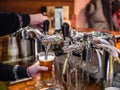 The barman pours beer into a glass in a small beer