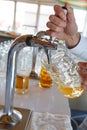 Barman pours a light foamy beer into a large mug during the Oktoberfest party. Royalty Free Stock Photo