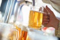 Barman pours a light foamy beer into a large mug during the Oktoberfest party. Royalty Free Stock Photo