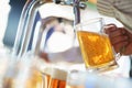 Barman pours a light foamy beer into a large mug during the Oktoberfest party. Royalty Free Stock Photo