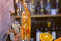 Pours liquor from jigger to Champagne flute with ice cubes with alcohol cocktail. Hands close-up. Royalty Free Stock Photo