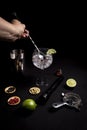 Barman preparing a gin and tonic cocktail on a black background next to his ingredients
