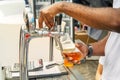 Barman`s hand holds a large glass in which fresh amber beer is poured with foam