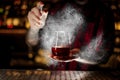 Barman sprinkling bitter into the glass with red sweet cocktail