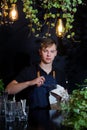 Barman waiter apron young glass fouger wipe black background cafe leaves flashlights evening light design