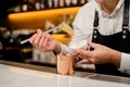 Barman in white shirt adding two slices of ginger into a cup Royalty Free Stock Photo