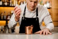 Barman in white shirt pouring alcoholic drink into a cup Royalty Free Stock Photo