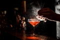 Barmans hands sprinkling the juice into the cocktail glass