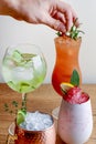 Barmans hans decorating four different assorted cocktail drinks made with alcohol and fruit served in unique glasses