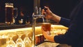 Barmen woman is pouring beer into the clean high glass