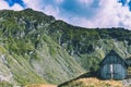 Barn in a mountain scenery with mountain in the background and puffy clouds above Royalty Free Stock Photo