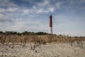 Barnegat Lighthouse, NJ, surrounded by sandy beach and golden wild grasses on a brisk winter day under blue cloudy sky Royalty Free Stock Photo