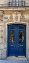 Elegant antique blue door of old building in Paris France. Vintage wooden doorway and ornate fretwork stone wall of ancient house Royalty Free Stock Photo