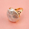 Baroque pearl gold ring on shimmering pink background