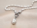 Baroque pearl necklace with pendant on beige leather background Royalty Free Stock Photo