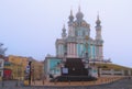 Baroque Saint Andrew\'s Church shrouded in fog during winter sunrise. Mysterious landscape view of Andriyivskyy Uzviz