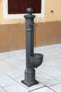 Baroque style iron pipe serving as hand water pump mounted on stone tiles of local town square next to old family house Royalty Free Stock Photo