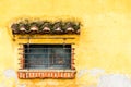 Barred & shuttered window in yellow wall, Central America