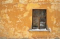 A barred window on the old yellow wall with a snow-covered window sill Royalty Free Stock Photo