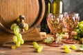 Barrel and glasses with wine and ripe grapes on wooden table Royalty Free Stock Photo
