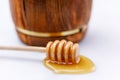 A barrel of honey and a wooden spoon with a drop of tasty liquid on a white background. Close-up