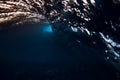 Barrel wave in ocean with warm sunset or sunrise tones. Underwater background with surfing wave