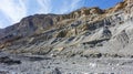 Barren and broken mountainsides with deep scars and exposed layers of rock a result of frequent landslides in the area