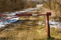 The barrier blocks the passage on a rural dirt road. Closed park area. The first snow on the dry grass along the roadside Royalty Free Stock Photo