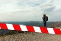 Barrier tape - quarantine, isolation concept, entry ban. Do not cross. Woman traveler with a hat standing on a background of green Royalty Free Stock Photo