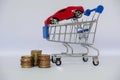 A barrow small shopping cart with coins on a white background for economizing  buying cars Concept of economizing and buying cars Royalty Free Stock Photo