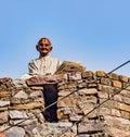 Barsana, India / February 23, 2018 - Old man sits on top of wall reading newspaper Royalty Free Stock Photo