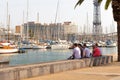 BARSELONA, SPAIN - AUGUST 6, 2019: A group of people sit in the shade and look at yachts in the port of Barcelona