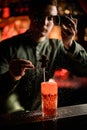 Bartender accurate decorates glass with cocktail with chocolate candy and sprinkles with powdered sugar Royalty Free Stock Photo