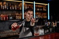 Bartender in apron adds ingredient to glass Royalty Free Stock Photo