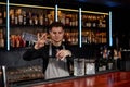 Bartender in apron adds ingredient to glass Royalty Free Stock Photo