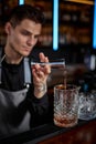 Bartender in apron adds ingredient to glass Royalty Free Stock Photo