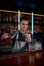 Bartender in apron adds ingredient to glass Royalty Free Stock Photo