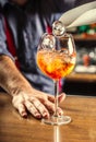 The bartender at the bar prepares the summer cocktail Spritz Veneziano, adds ice cubes to the drink Royalty Free Stock Photo