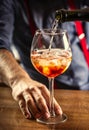 The bartender at the bar prepares the summer cocktail Spritz Veneziano, pours Prosecco into a glass with ice Royalty Free Stock Photo