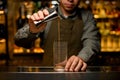 bartender carefully pours drink into transparent glass on the bar counter. Front view Royalty Free Stock Photo